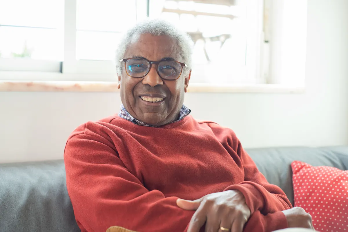 Senior man smiling beside a window in his home